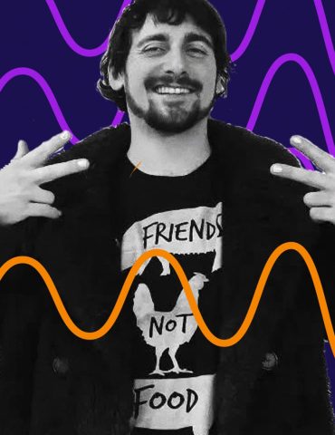 DJ Keano smiles and makes peace signs to the sides of his shoulders