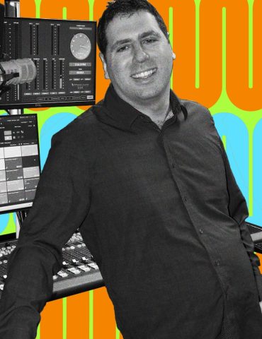 Matt leans back while smiling at the camera, recording equipment behind him