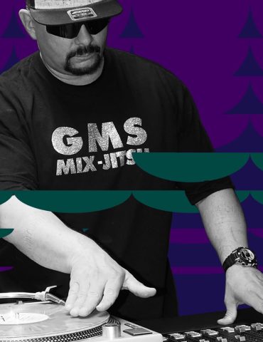 Grandmaster GMS DJs, with one hand on vinyl record and the other on mixer