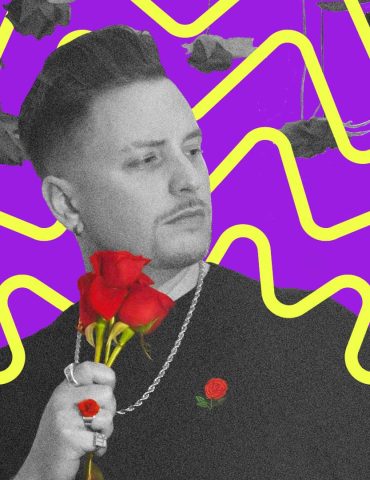 Grayson rose, mostly in black and white, holds a bouquet of red roses, with a red rose ring and a red rose print on his shirt, while holding a hand up to touch black & white roses
