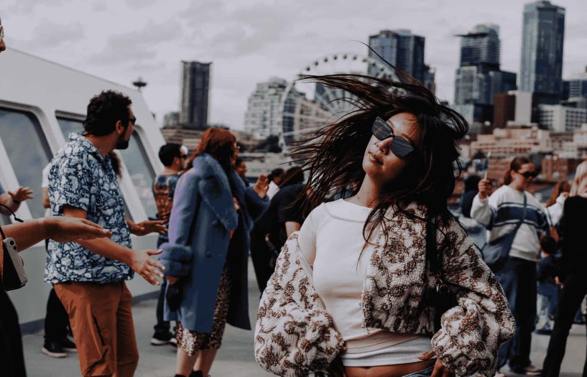 A photo of a woman flipping her hair while dancing in front of the Seattle skyline