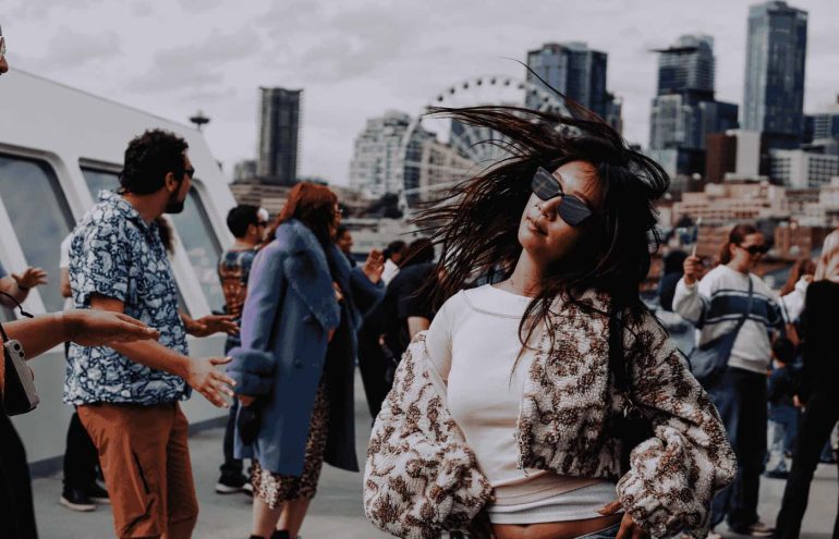 A photo of a woman flipping her hair while dancing in front of the Seattle skyline